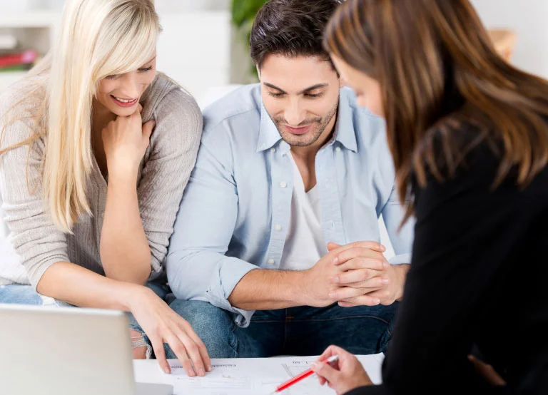 Couple examinant des documents avec une courtière hypothecaire.